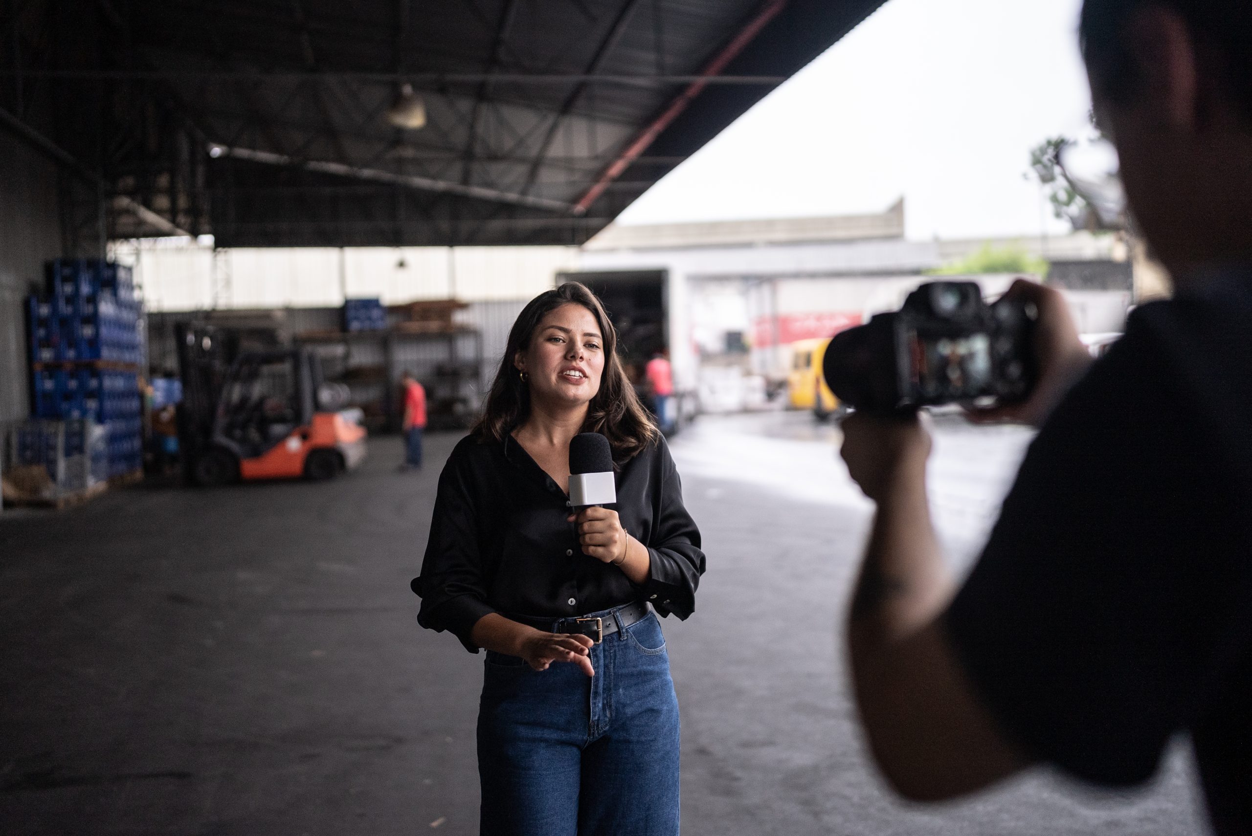 Television reporter standing in front of a warehouse